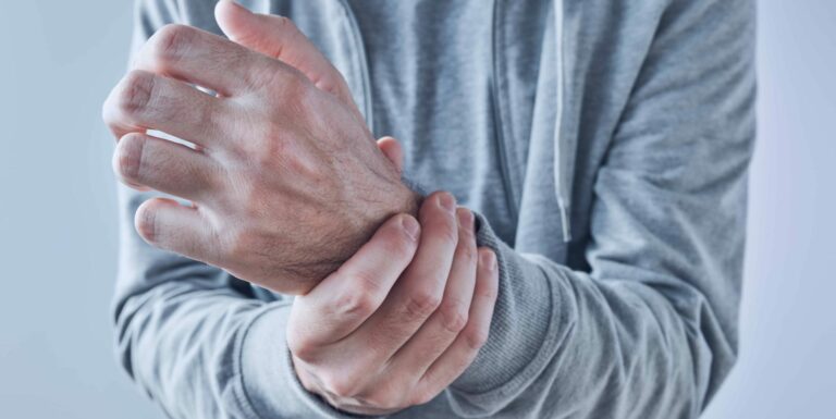 man holding his left wrist with his right hand